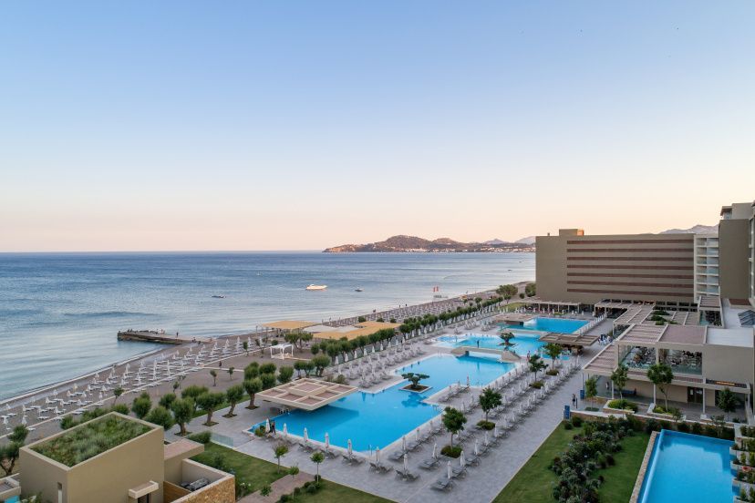 Blick auf das Amada Colossos Resort auf Rhodos mit großen Pools, Liegebereichen und direktem Zugang zum Strand.