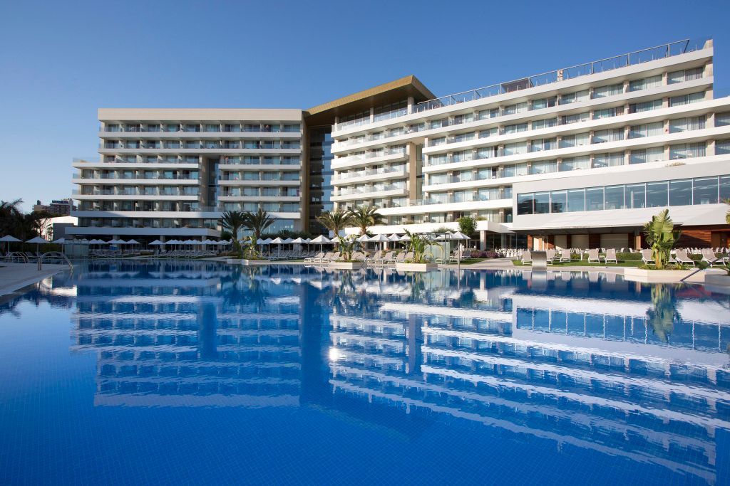 Moderner Hotelkomplex des Hipotels Playa de Palma Palace mit weitläufigem Außenpool, Sonnenterrasse, Liegen und Palmen – perfekte Kulisse für entspannte Urlaubstage auf Mallorca.