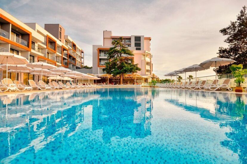 Hotel Sentido Marea am Goldstrand mit großem Außenpool, weißen Sonnenliegen und modernen Gebäudekomplexen bei Sonnenuntergang.