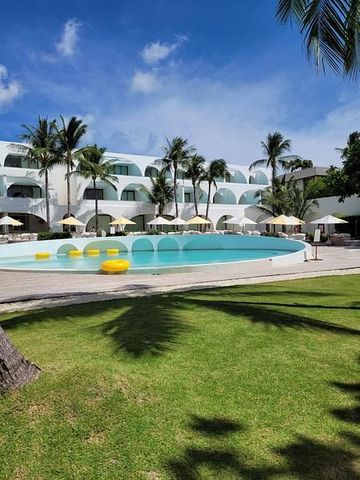 Pool mit Rasen und Palmen vor den weißen Bogenbauten des Sala Samui Resort