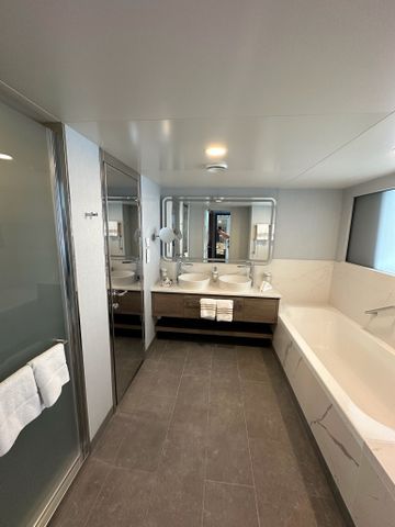 Bad mit Badewanne und Doppelwaschtisch in einer Suite der Mein Schiff Relax