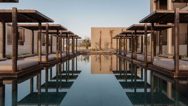 Eleganter Poolbereich im Casa Cook Samos mit modernen Holzpergolen, gemütlichen Daybeds direkt am Wasser und minimalistisch gestalteter Architektur in warmen Naturtönen.