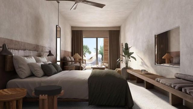 Modern eingerichtetes Hotelzimmer im Cooks Club Kolymbia mit neutralen Naturtönen, gemütlichem Doppelbett, Deckenventilator, Sitzbereich, großen Spiegeln und Zugang zu einer Terrasse mit Blick auf Palmen und Hängematten.