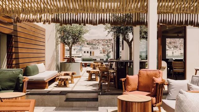 Stilvoll gestaltete Rooftop-Terrasse mit gemütlichen Loungemöbeln, Pflanzen, Holzelementen und Stadtblick im MonAsty Thessaloniki – entspanntes Outdoor-Ambiente mit Designfaktor.